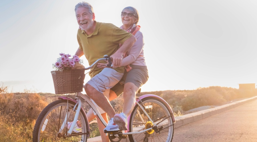 Elderly couple riding a bike in sunset