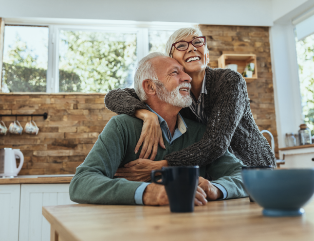 Happy elderly couple smiling together in their home enjoying financial freedom through Chip Reverse Mortgage