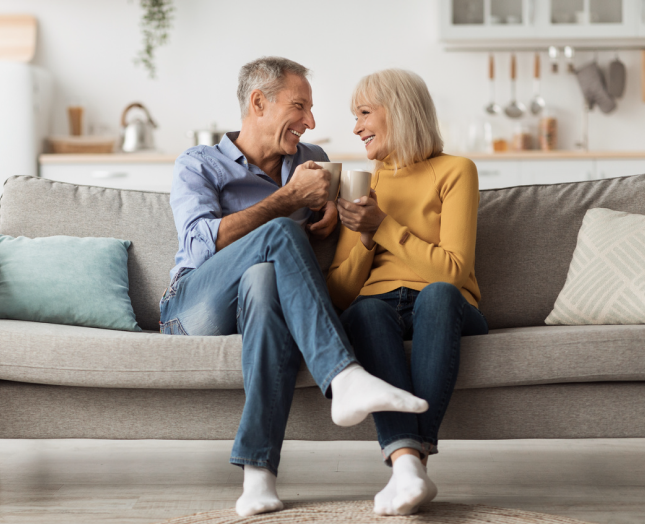 Happy elderly couple smiling and enjoying coffee in their home, highlighting financial freedom via CHIP Reverse Mortgage