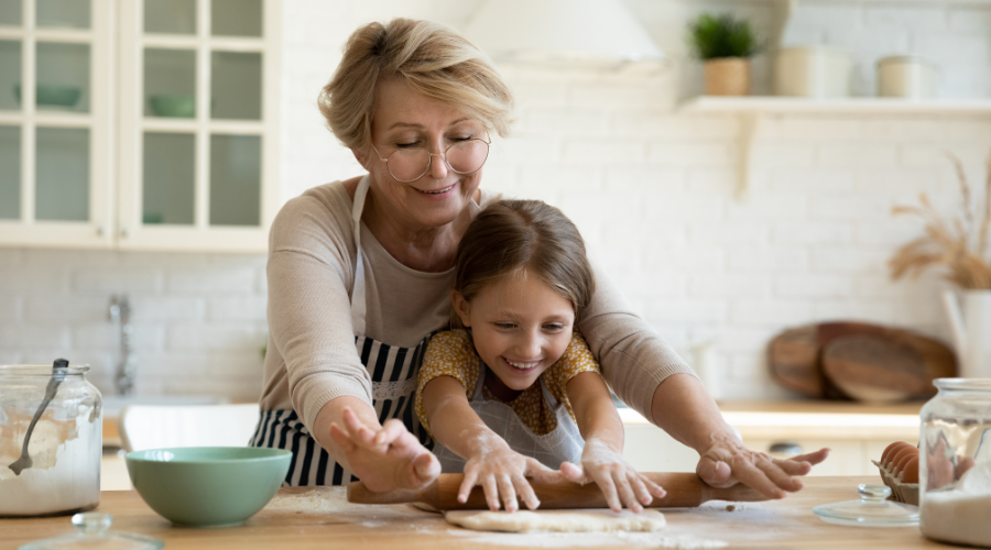 Woman and granddaughter smiling and baking together